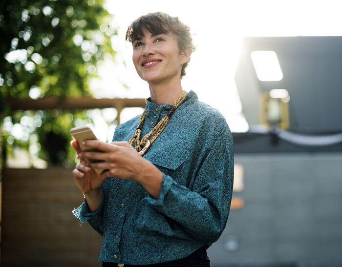 A small business owner smiling at her phone outside her premises